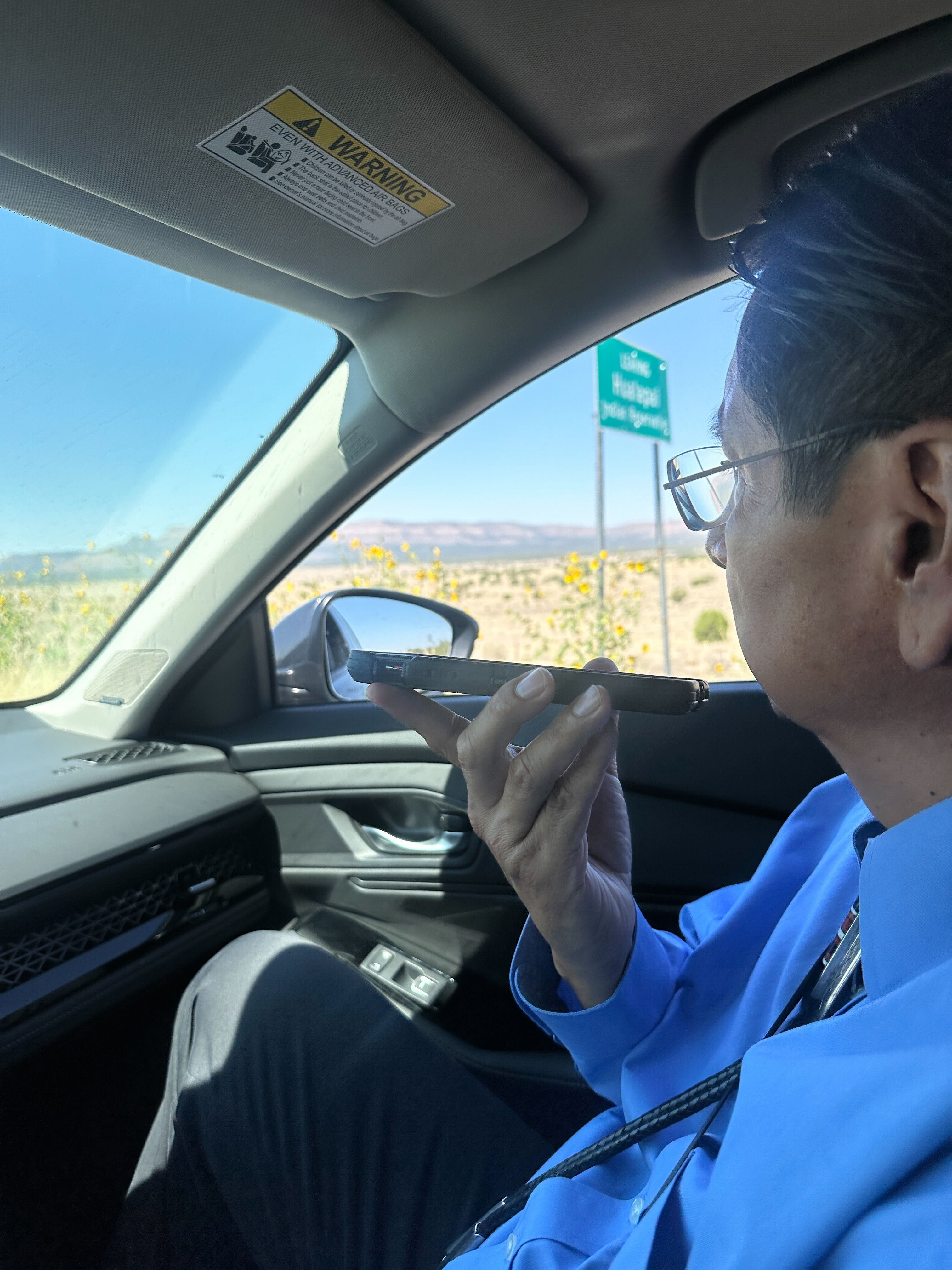 photo of Jonathan Nez making calls from the passenger seat of a car